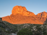 A tall peak is lit by the rising sun.