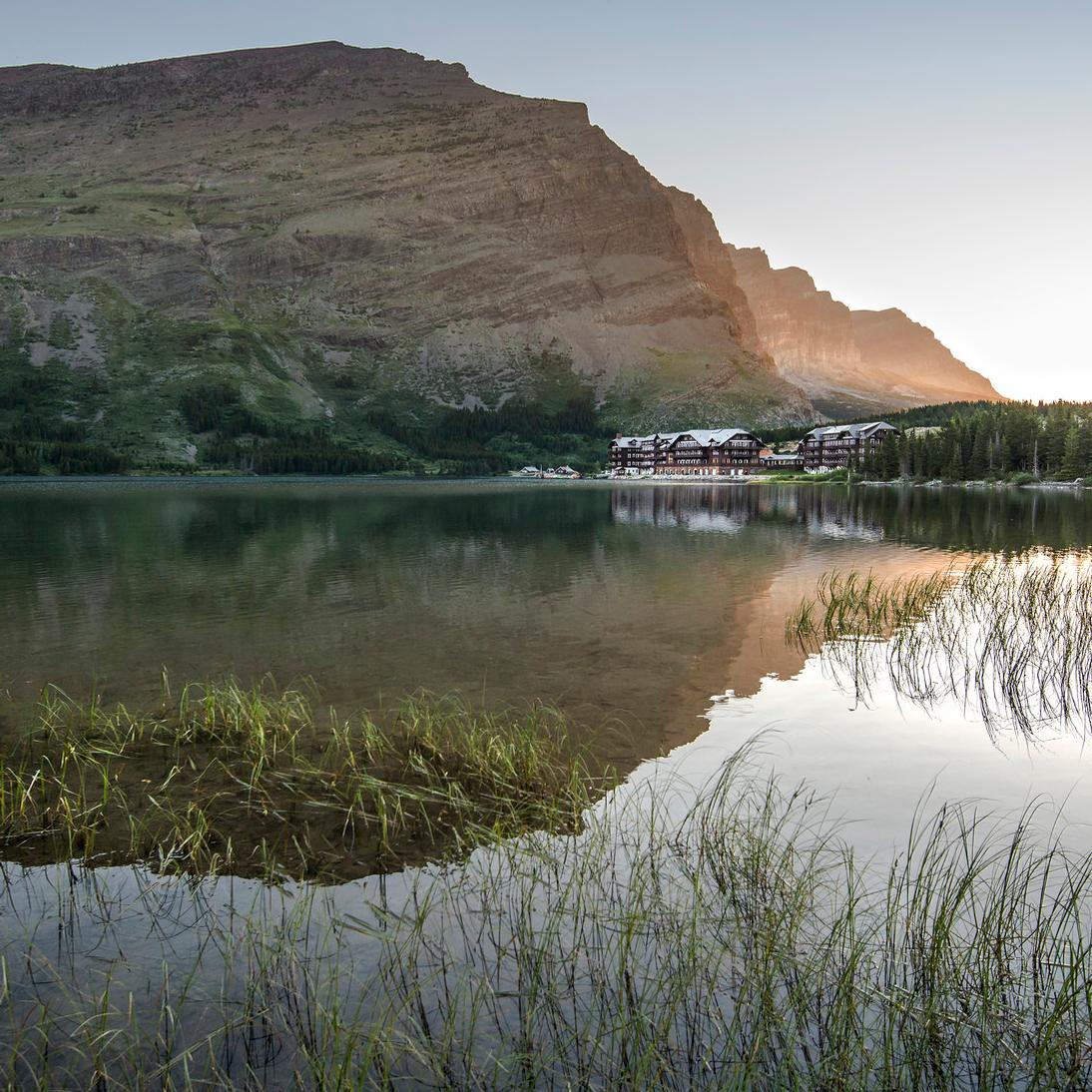 Watching sunrise from lakeshore with large hotel across the water and mountain reflected