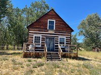 Historic log cabin with steps leading to a small door.