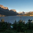 Tiny rocky island in the middle of large lake surrounded by trees and mountains