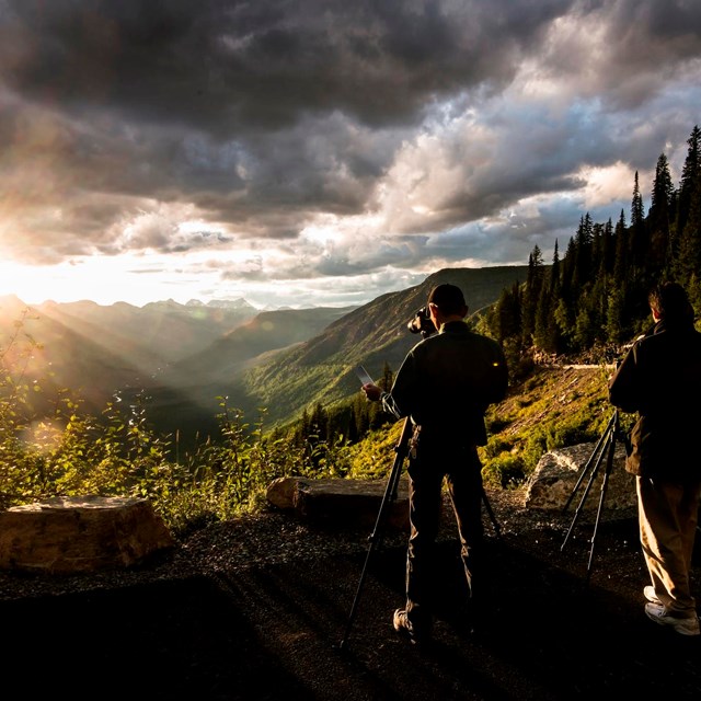 Two men photographing sunset over western mountain range