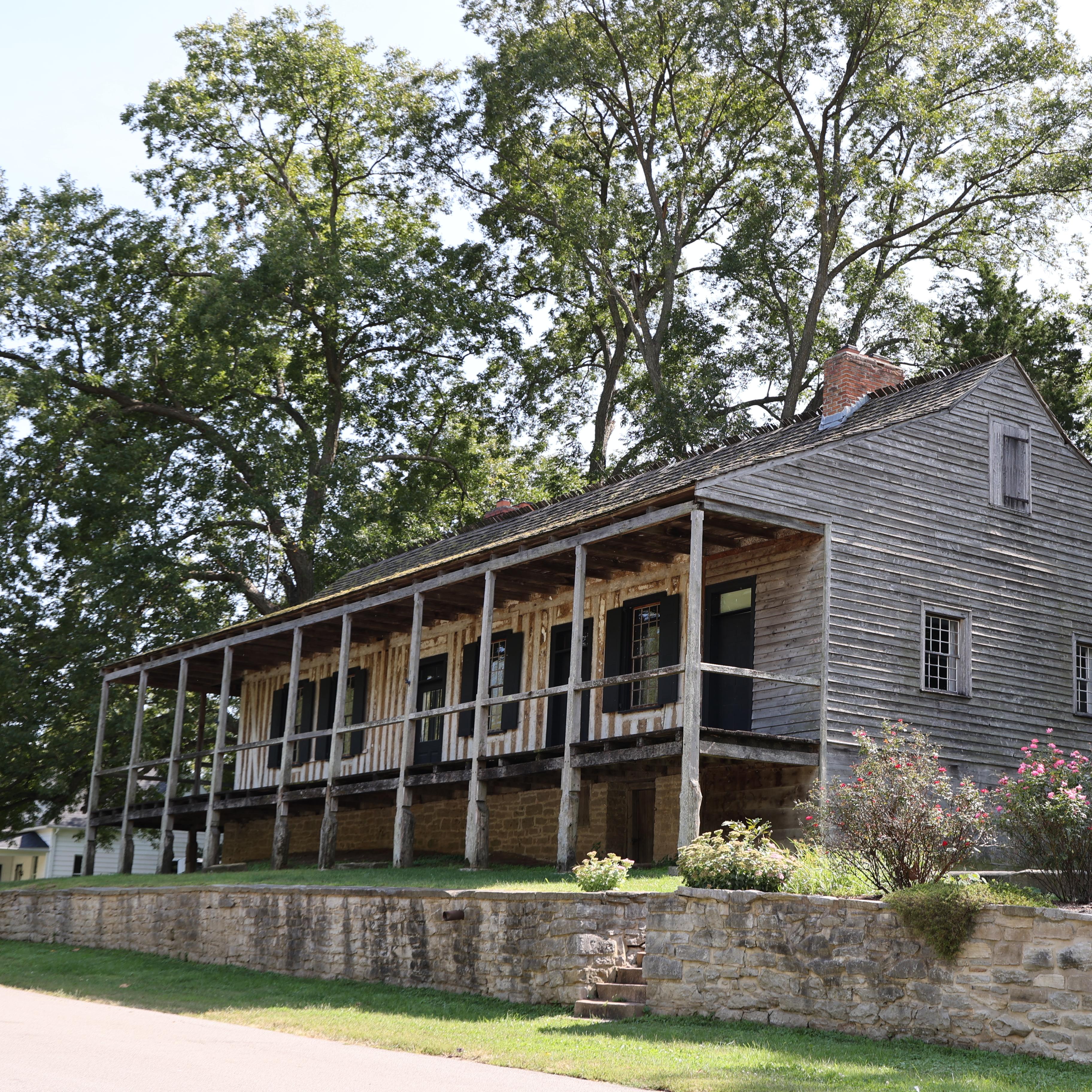 A large vertical log home with a wraparound porch.
