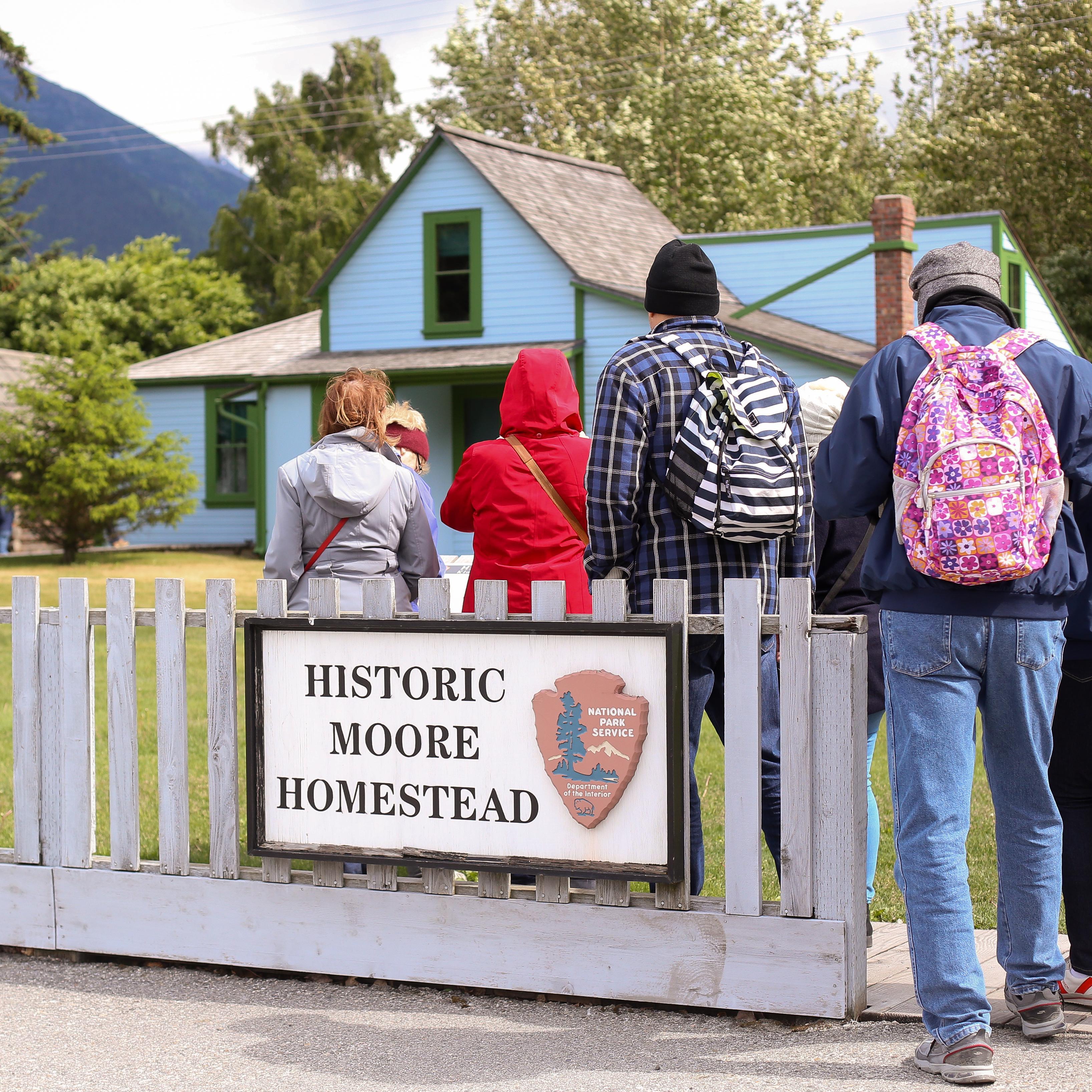 People gathered in front of a house with fence sign 