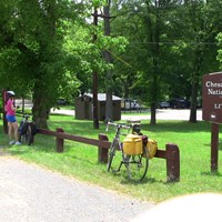 bicyclists stopped along a natural surface path near a modern and an historic historic