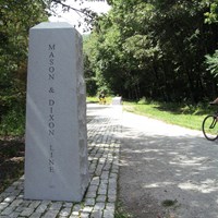 a granite obelisk next to a ten-foot wide crushed stone pathway 