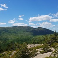 view of two mountains in the distance from the summit of another mountain