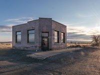 Color photograph of a one-story white neoclassical building surrounded by a bright desert