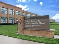 A brick entrance sign sets in front of a large brick building.