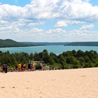 Looking down from top of sand dune to teal lake surrounded by dark green trees