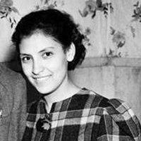 Black and white photo of a young woman in a plaid dress.