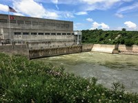 Large concrete structure on the left, with water flowing beneath it and then downstream
