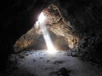 A beam of light shines down from above, illuminating rock walls