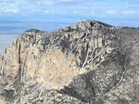 A yellow cliff face rises in the distance, defining a mountain peak.