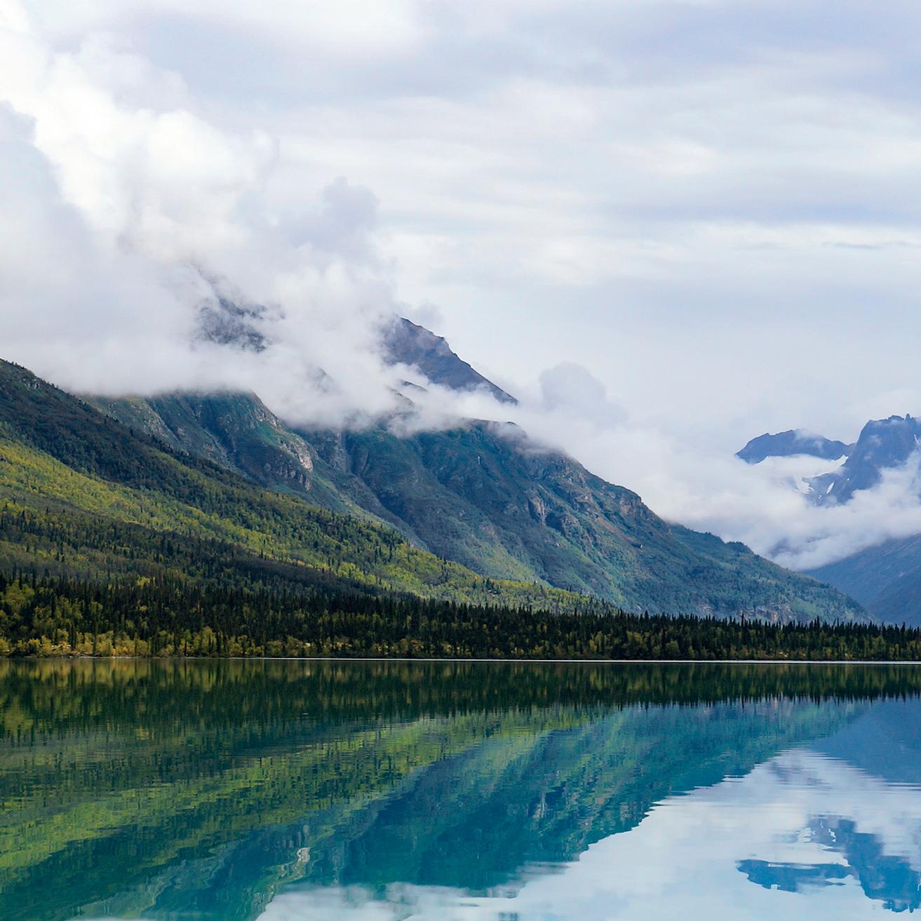 Mountains and yellow trees reflect in blue waters
