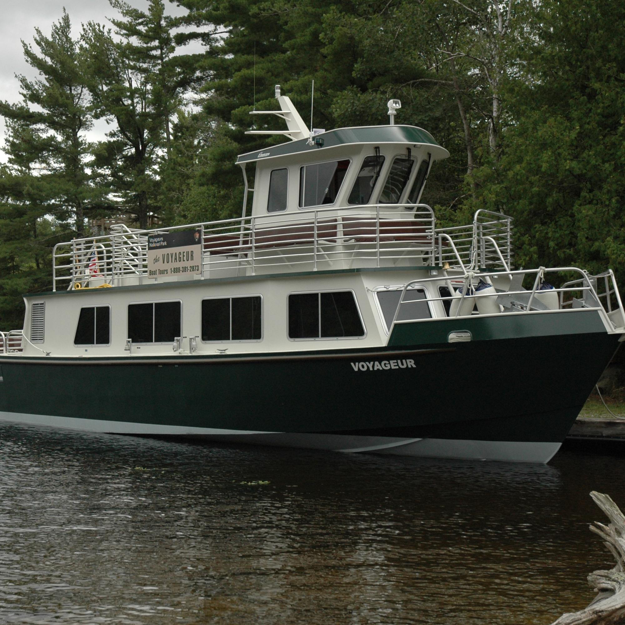The park tour boat docked at Kettle Falls with trees in the background