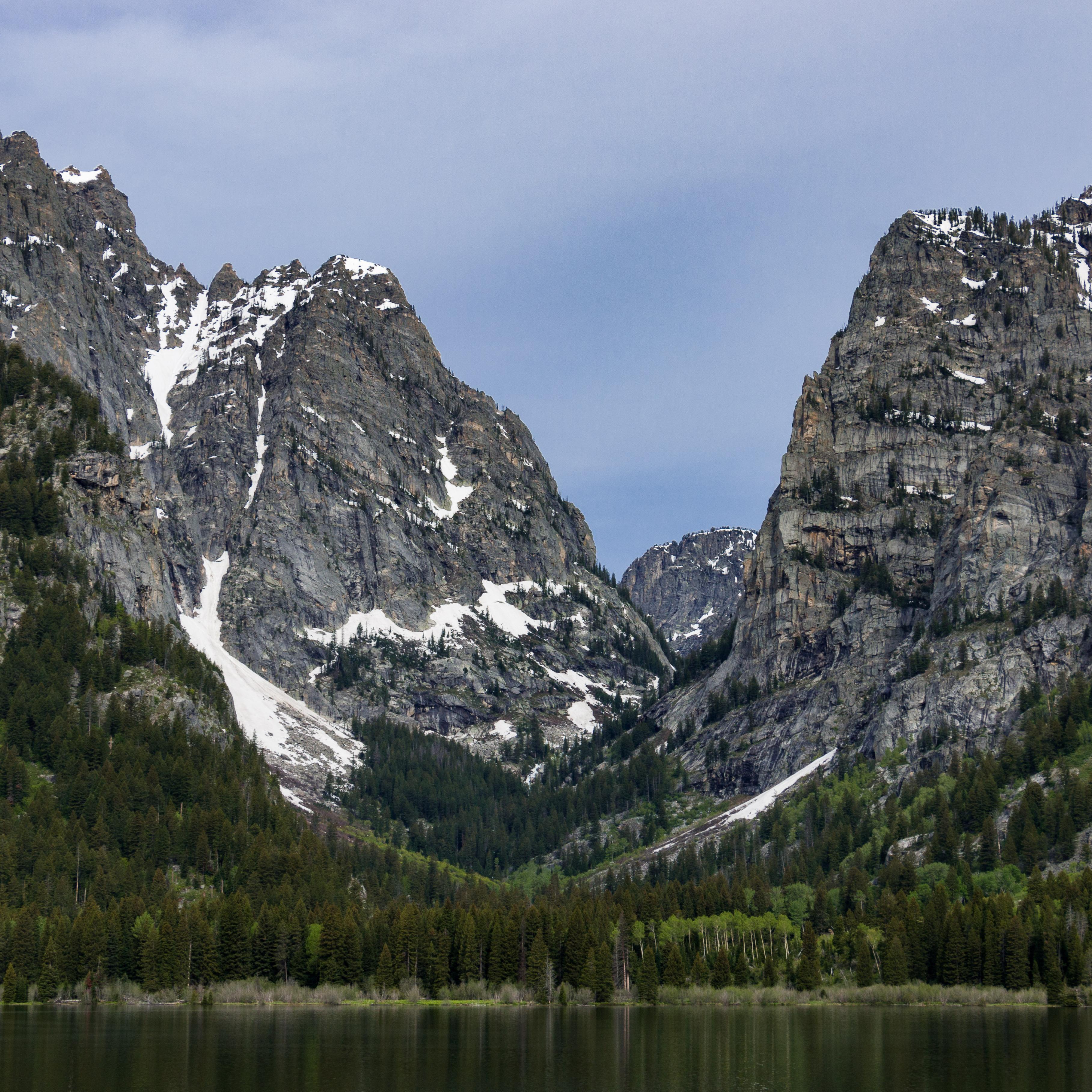 A rocky, mountain canyon sits across a calm lake.