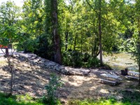 A stone staircase descends a wooded riverbank down to the water; two picnic tables to the right.