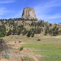 people walking along a dirt path through the prairie dog town, Devils Tower in the background