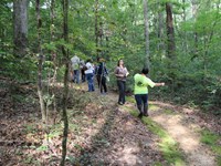 A dirt path in a forest with several teenage students walking and swinging their arms.