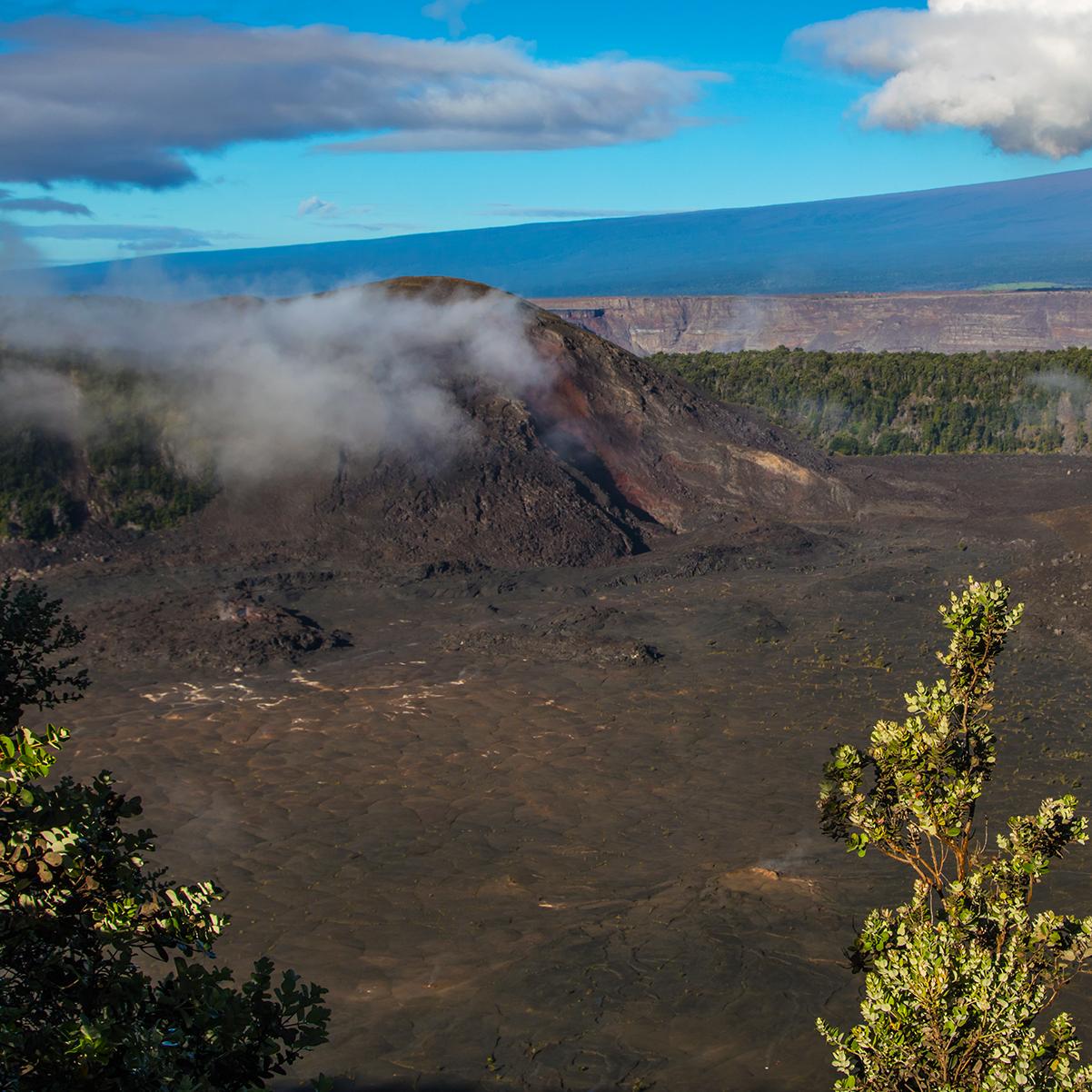 Volcanic crater with a large cinder cone on the left-hand side and a larger mountain beyond.