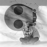 Man sitting on concrete floor outdoors in front of ladybug design on wall