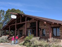 A wooden and stone building with a short set of steps leading up to a peaked roof and entryway.