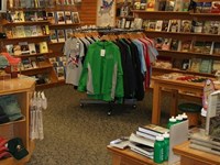 A room with shelves of books and other items. Tables and clothing racks in the middle.
