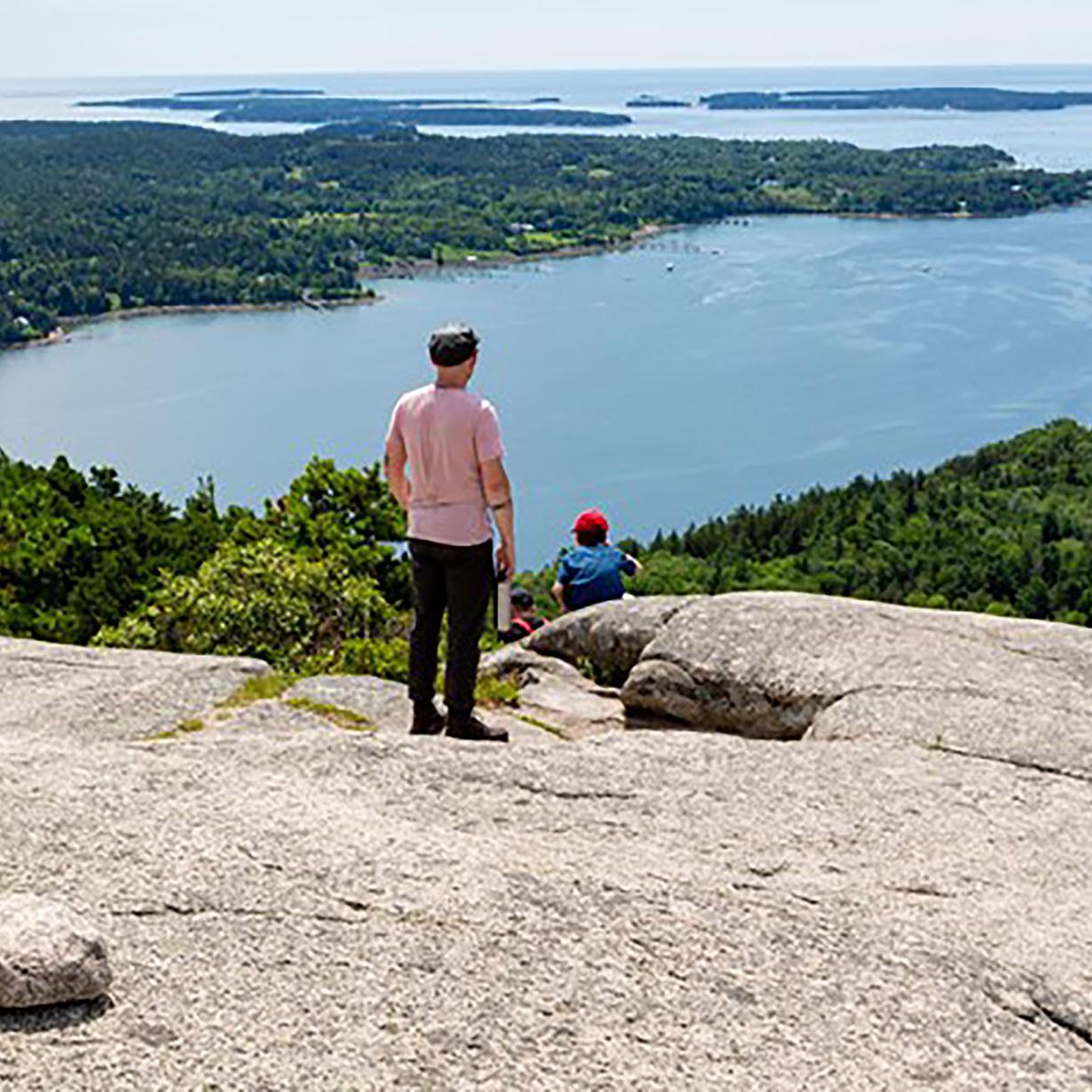 Visitors overlook islands from a mountain summit. 