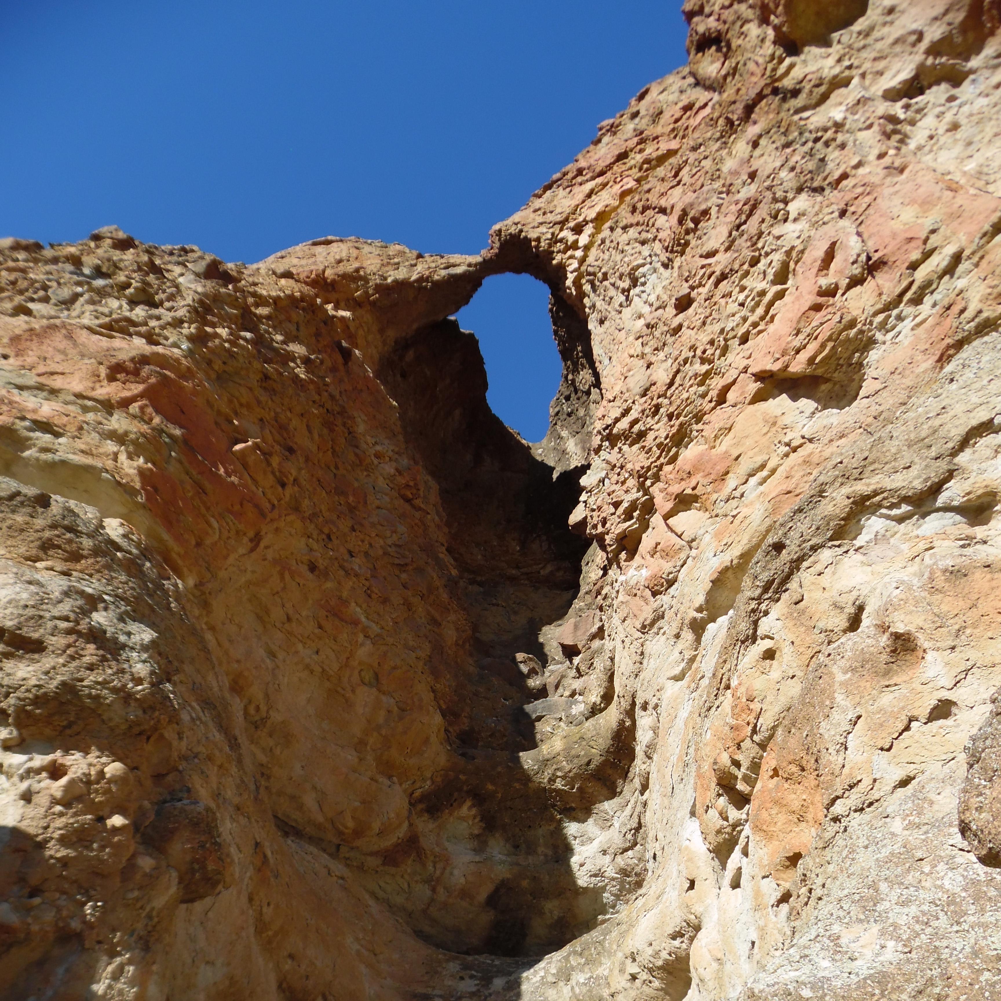A small rock arch at the top of a cliffside formed from erosion