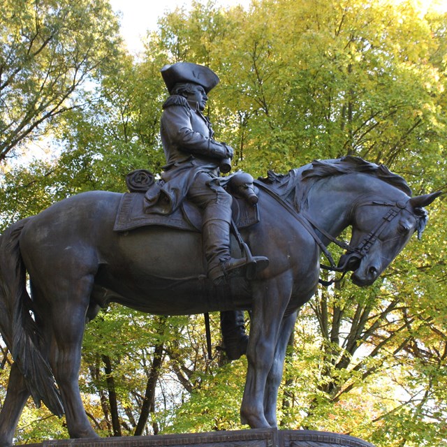 Dark bronze statue of an American Revolutionary War officer atop a bowing horse.