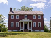Front view of 2.5 story red farmhouse.