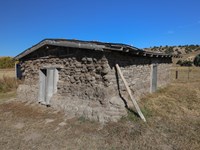A small square house made out of dirt bricks, with one opening on each side and a roof.