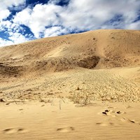 Sand dunes under a cloudy blue sky