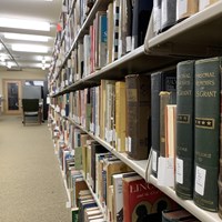 Library shelves in a basement room stacked with books across the shelves.