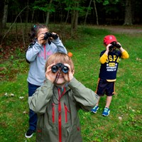 Three children hold up binoculars to watch wildlife in Acadia National Park.