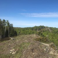 The trail crosses an exposed rocky ridge surrounded by forest.
