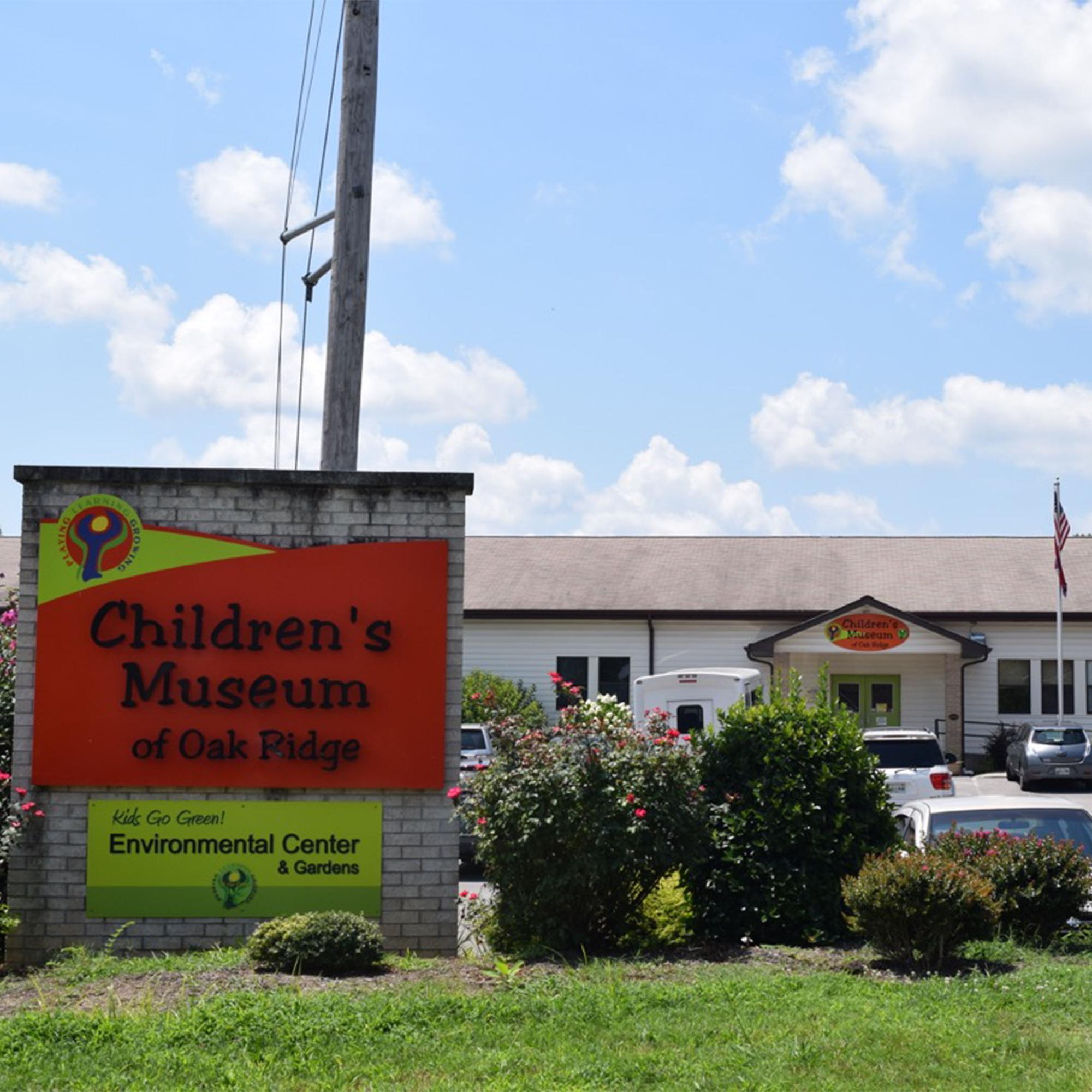 A large sign in front of a parking lot and school building.