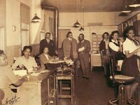 African American women and men dressed in business clothes are working in an office.