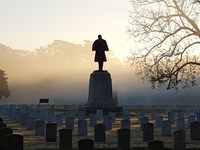 Statue of a soldier standing over graves in a cemetery