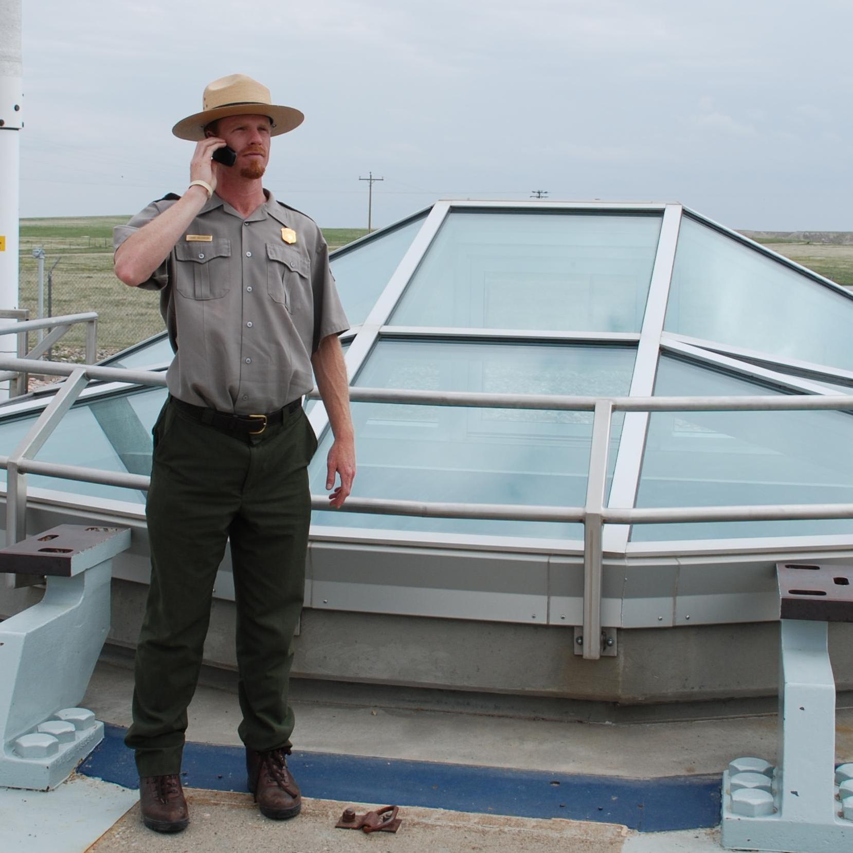 A park ranger stands in front of a glass enclosure at a missile silo