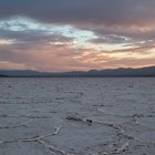 A vast salt flat stretches into the horizon with a cloudy sunset sky.