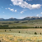 Snow-covered mountains stand above the wide valley covered in sagebrush-steppe.