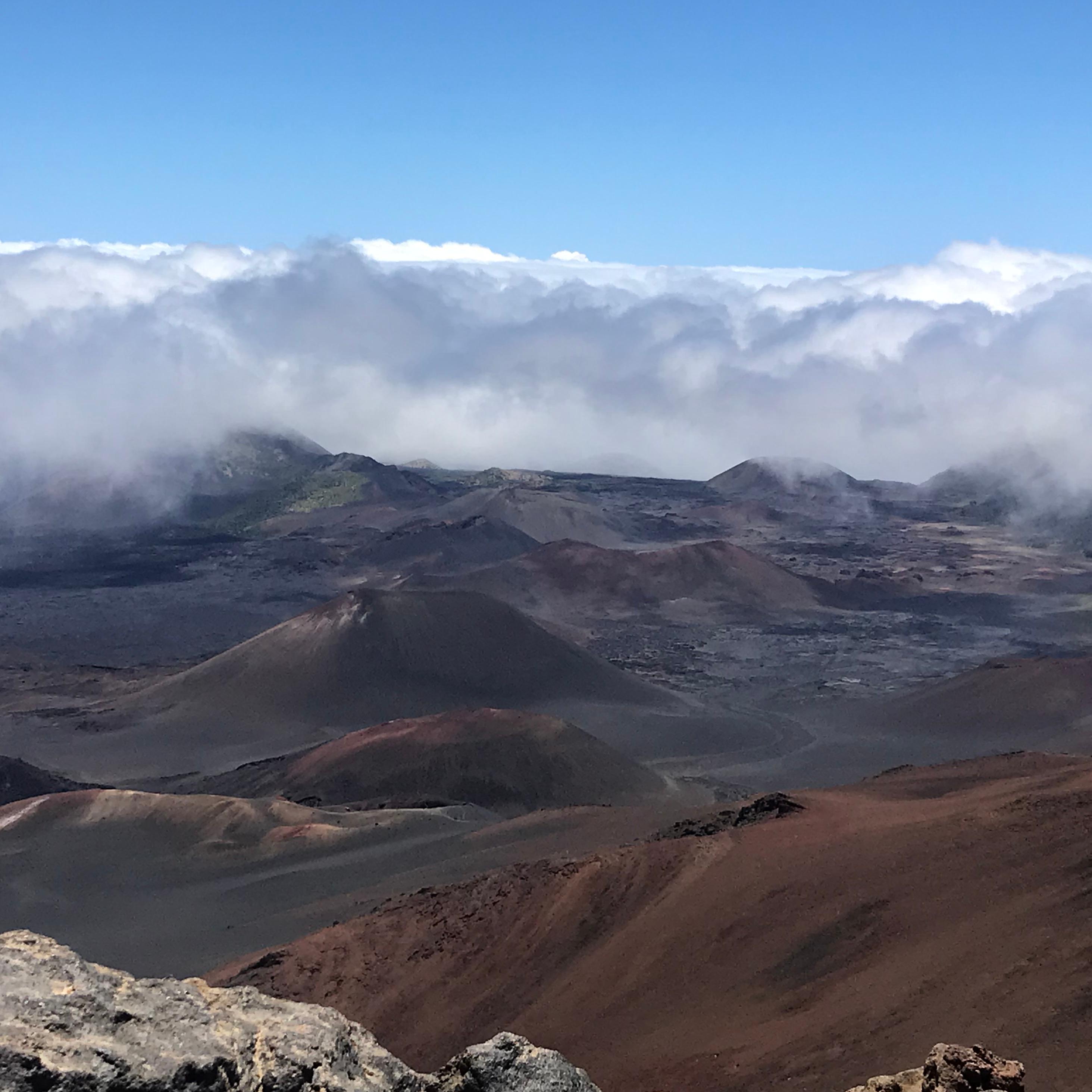 Clouds begin to fill in a volcanic valley dotted with cinder cones.