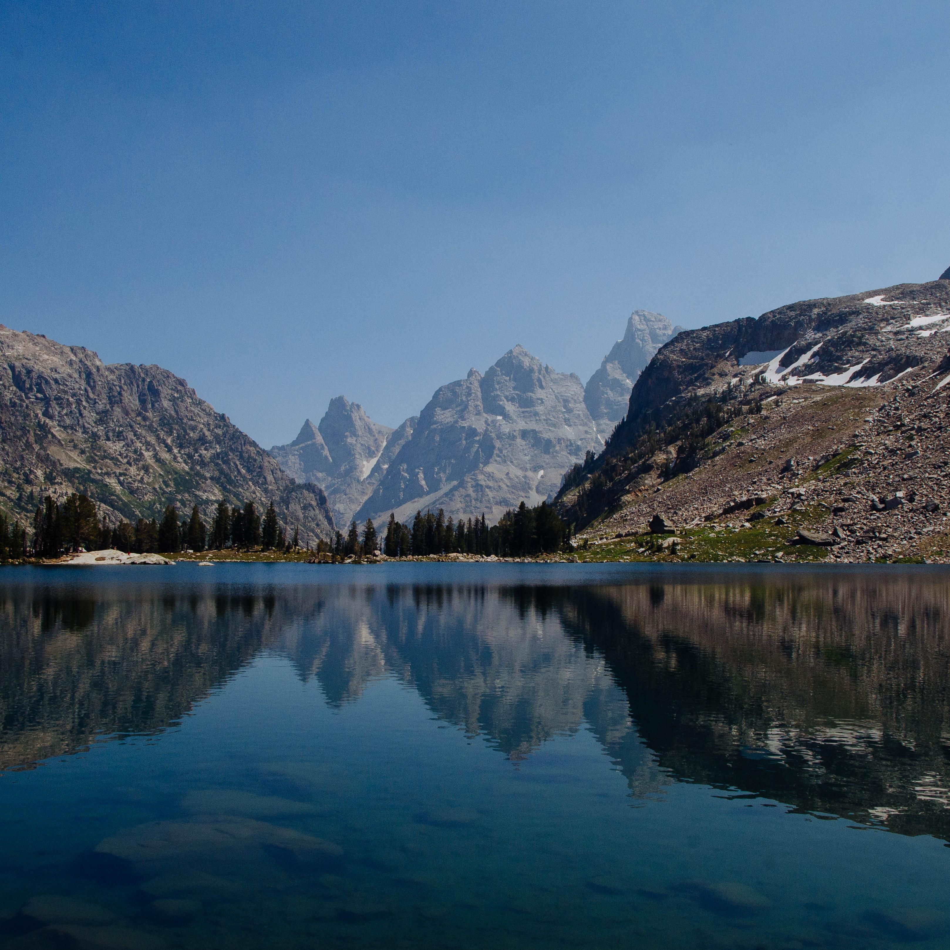 A small lake surrounded by mountains reflects the mountainous scenery on its calm surface.