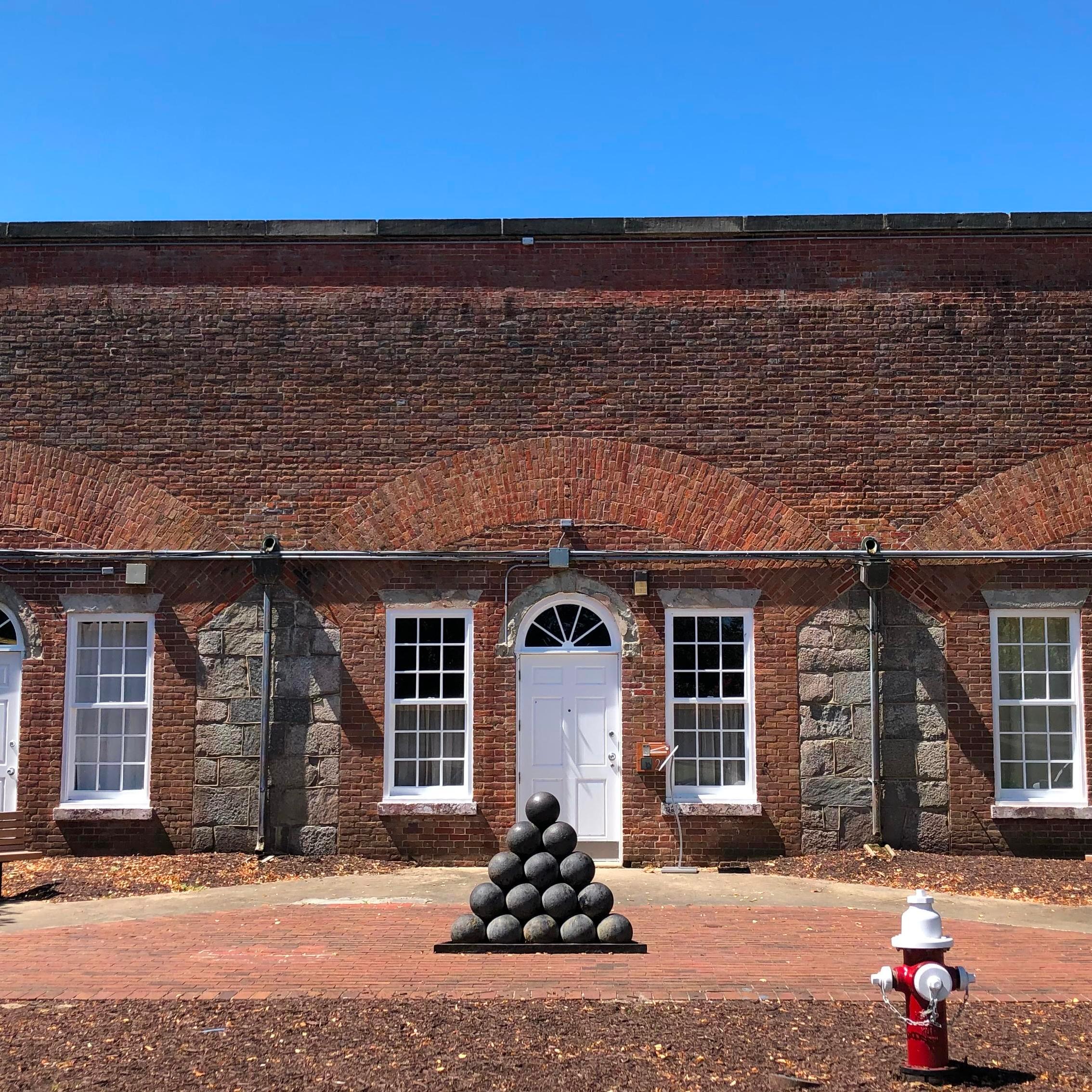A pyramid of stacked cannon balls marks the entrance to a museum built into a brick fort.