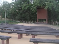 rows of curved benches around a flat stage area with screen and fire pit