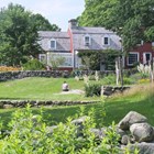A person sits on the grass painting a red building.