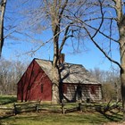 A photo of the historic Wick House in Jockey Hollow, contrasting green grass and red building.