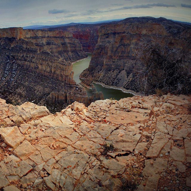 A massive canyon with multicolored walls and a river far below.