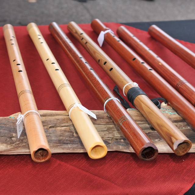 Wooden flutes lined up on red cloth